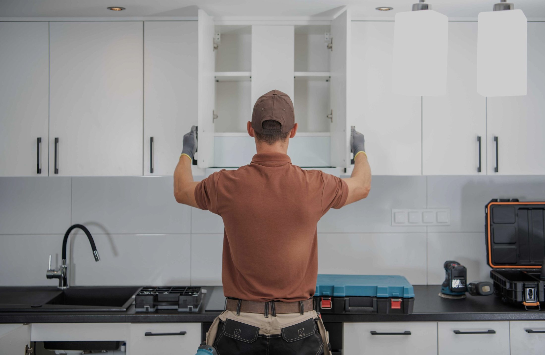 A fitter checking wall cabinet doors and alignment before handover
